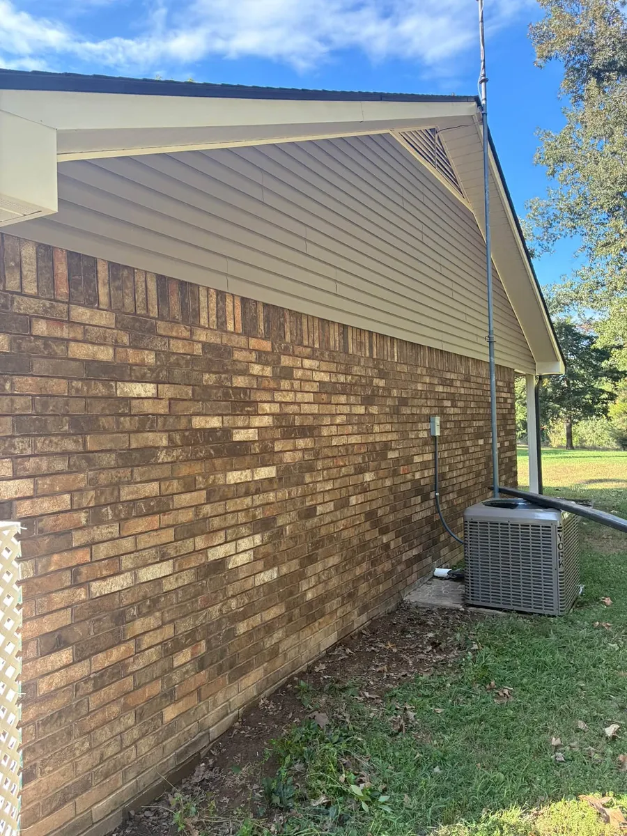 Brick wall with a gable end and an air conditioner beside a lawn