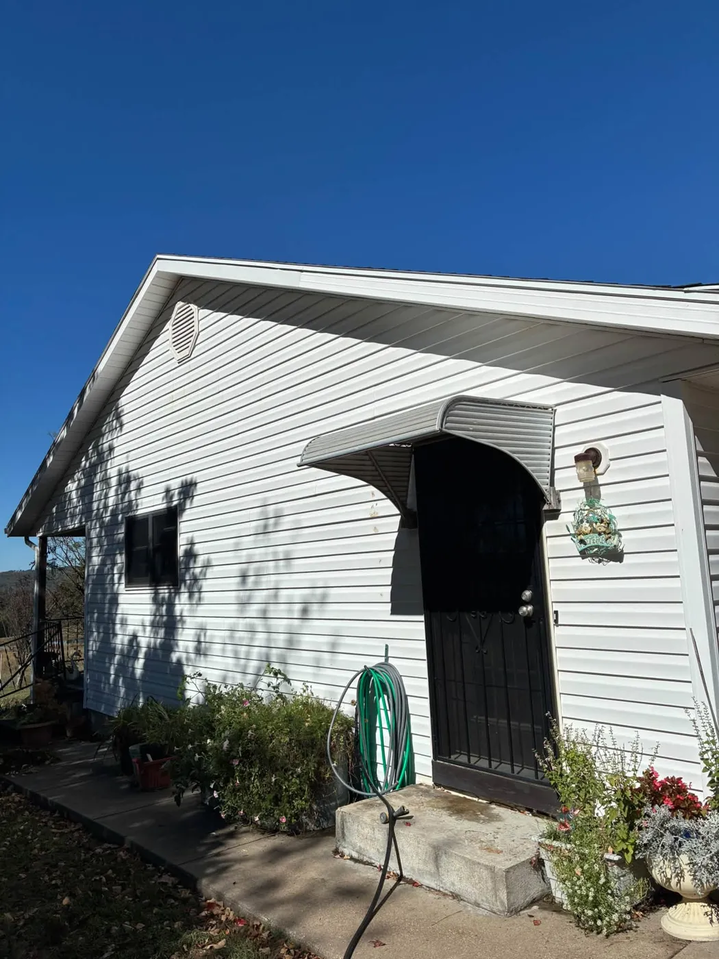 White sided house with a black security door, washed clean