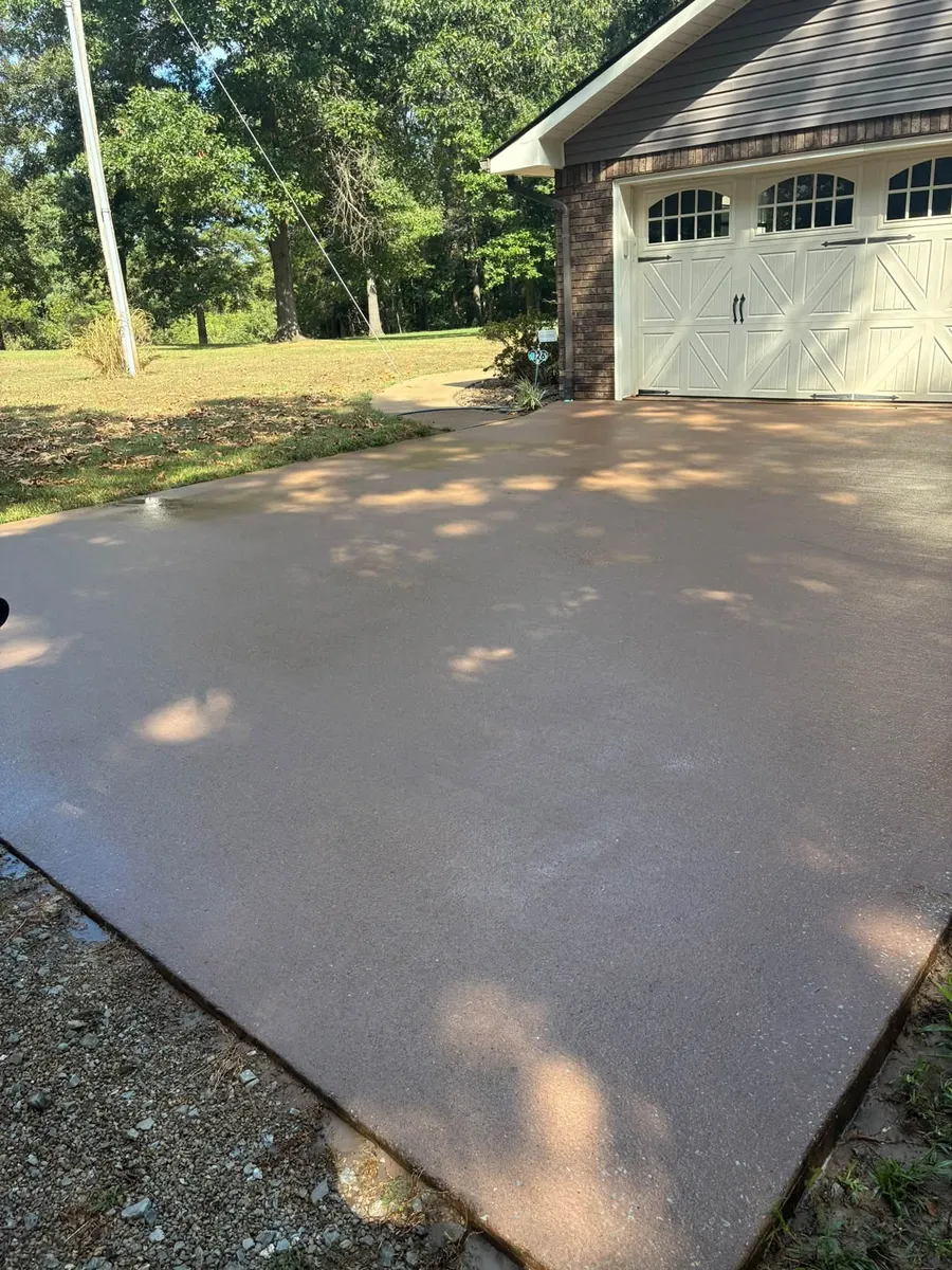 Clean concrete driveway beside a brick garage with cream carriage doors