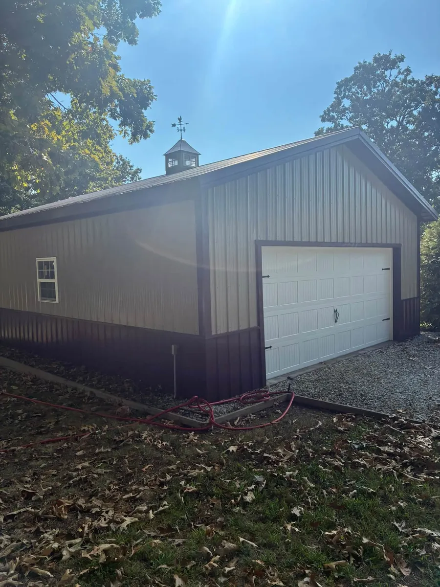 Two-car metal garage in tan and burgundy with a white garage door and a cupola