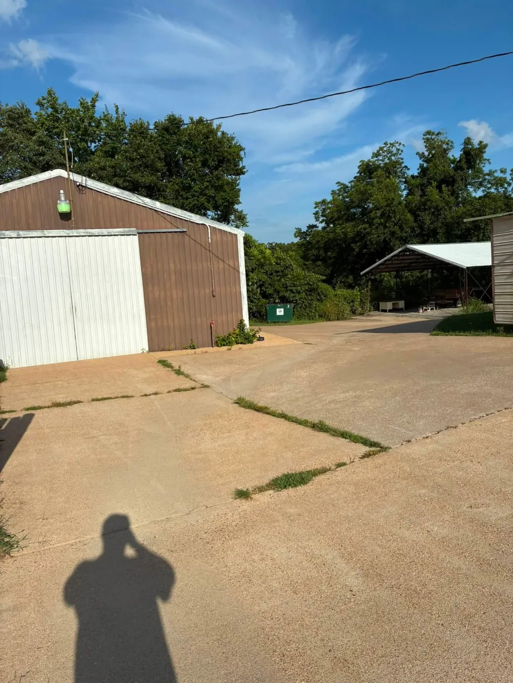 Clean concrete lot in front of a metal building and shed