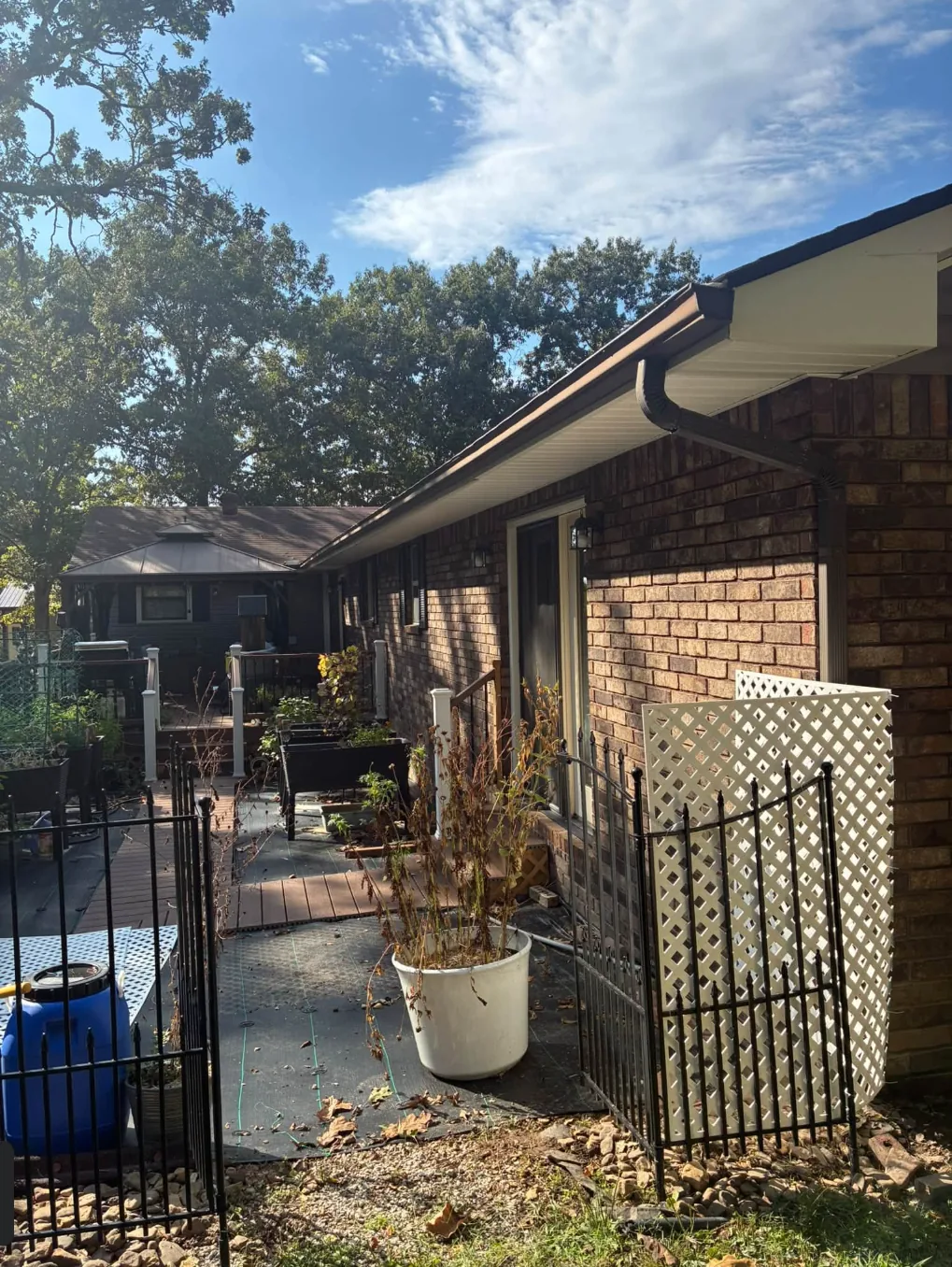Brick ranch house with a clean brown gutter, a back deck and a fenced yard