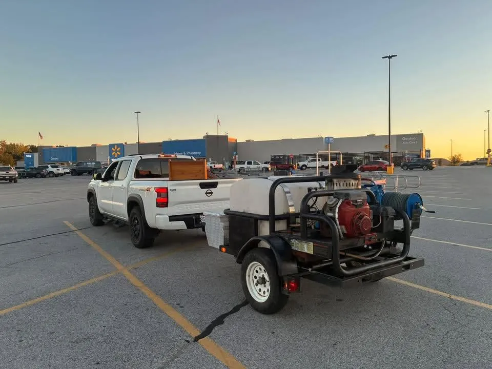 Poncho's work truck and trailer-mounted pressure washer parked in a lot at sunset