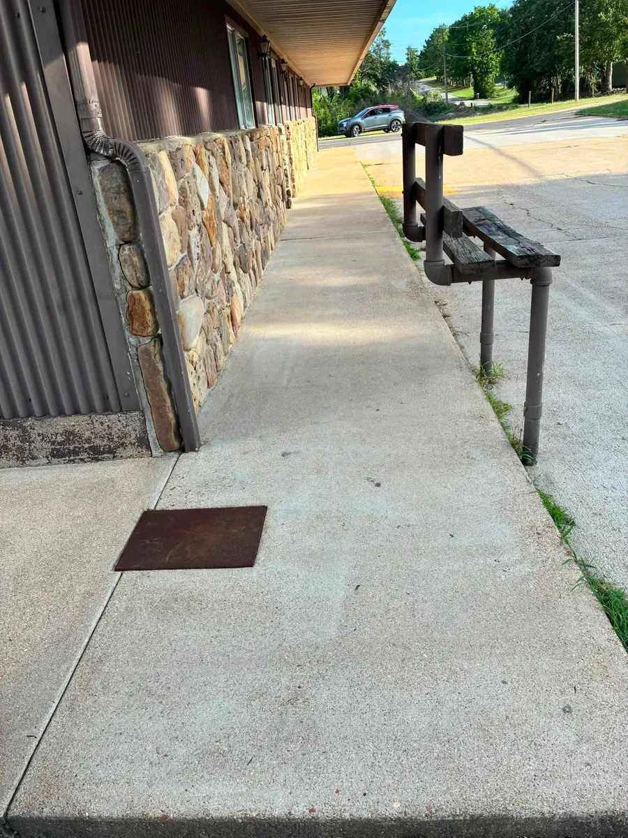 Clean sidewalk along a stone-front building with a metal railing