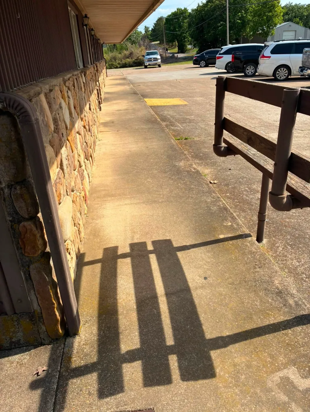 Dirty sidewalk along a stone-front building with a metal railing